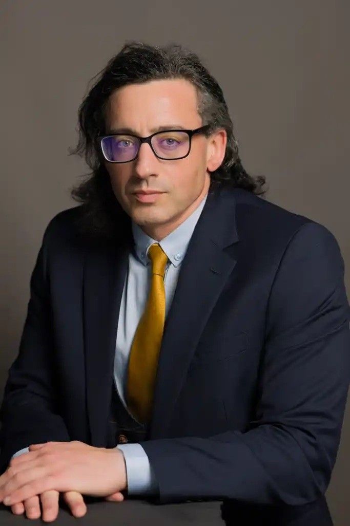 Simon Ridding, wearing a navy suit and mustard tie